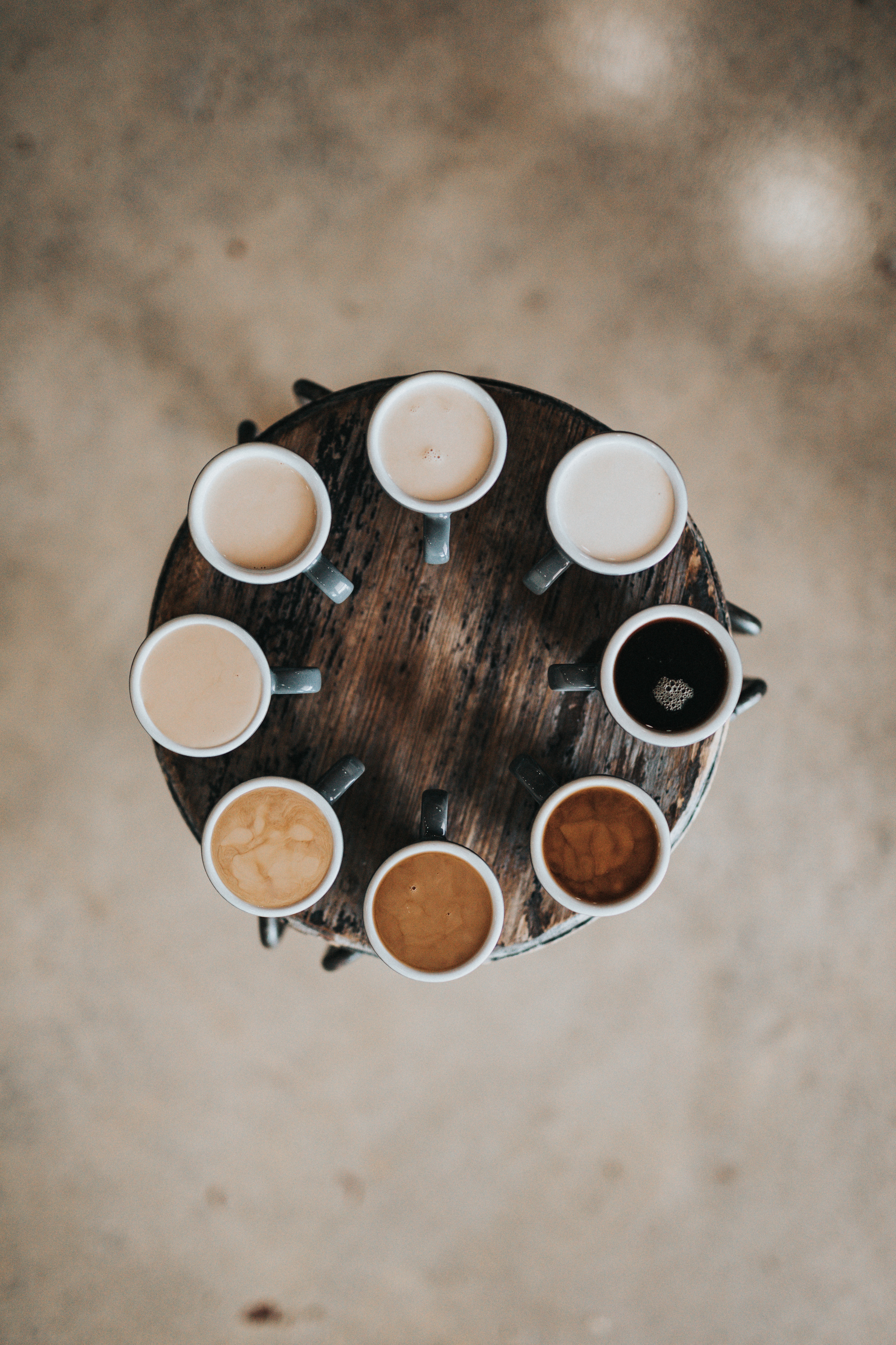 Cups of coffee on a round table in various shades due to creamer.