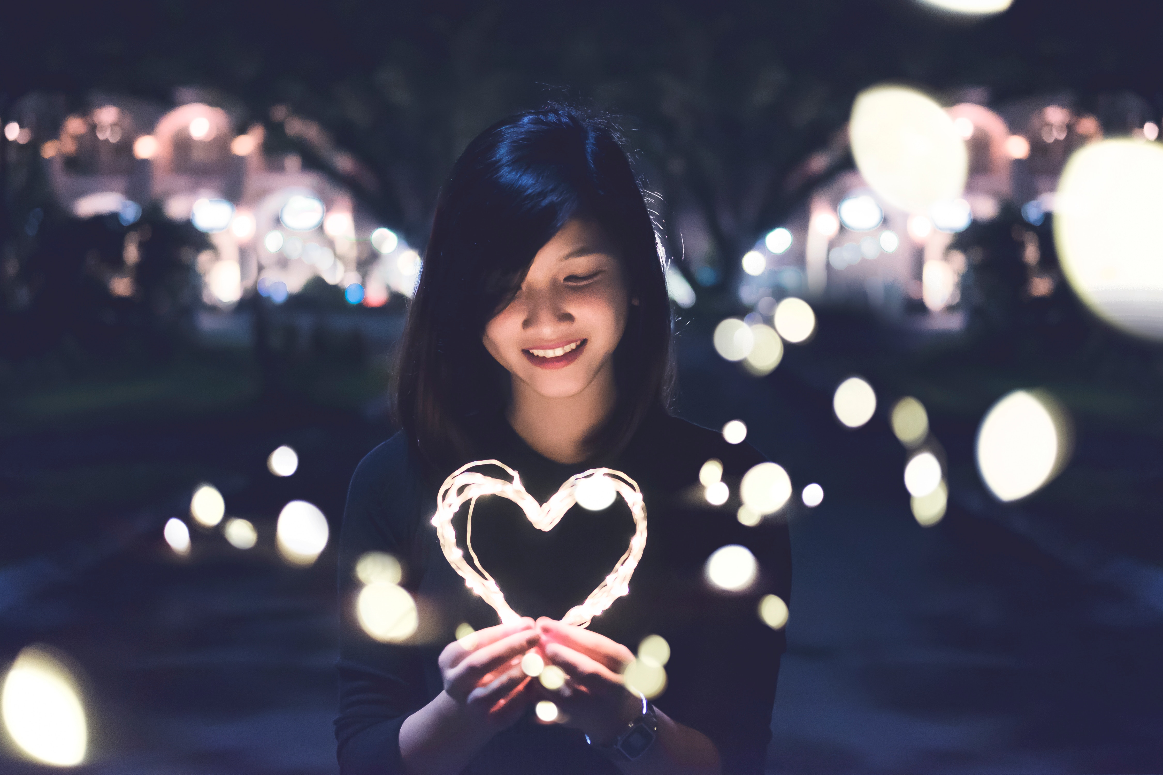 Woman smiling holding lights shaped as a heart.