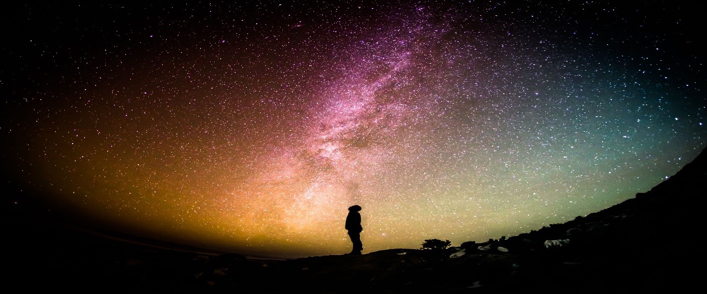 Person looking at a brilliant nigh sky as stars dance in color.