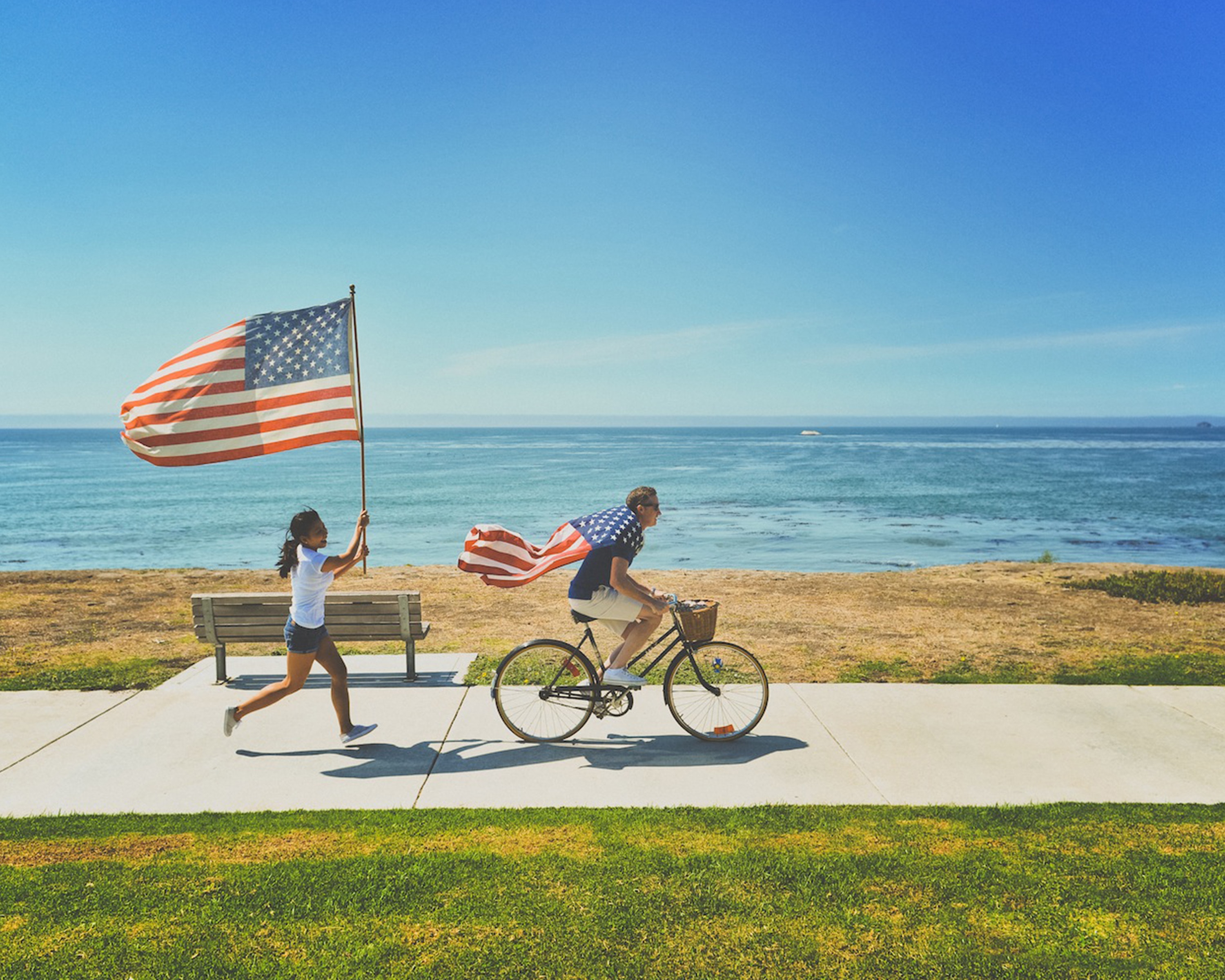 USA Flags , one girl running behind a boy on a bike.