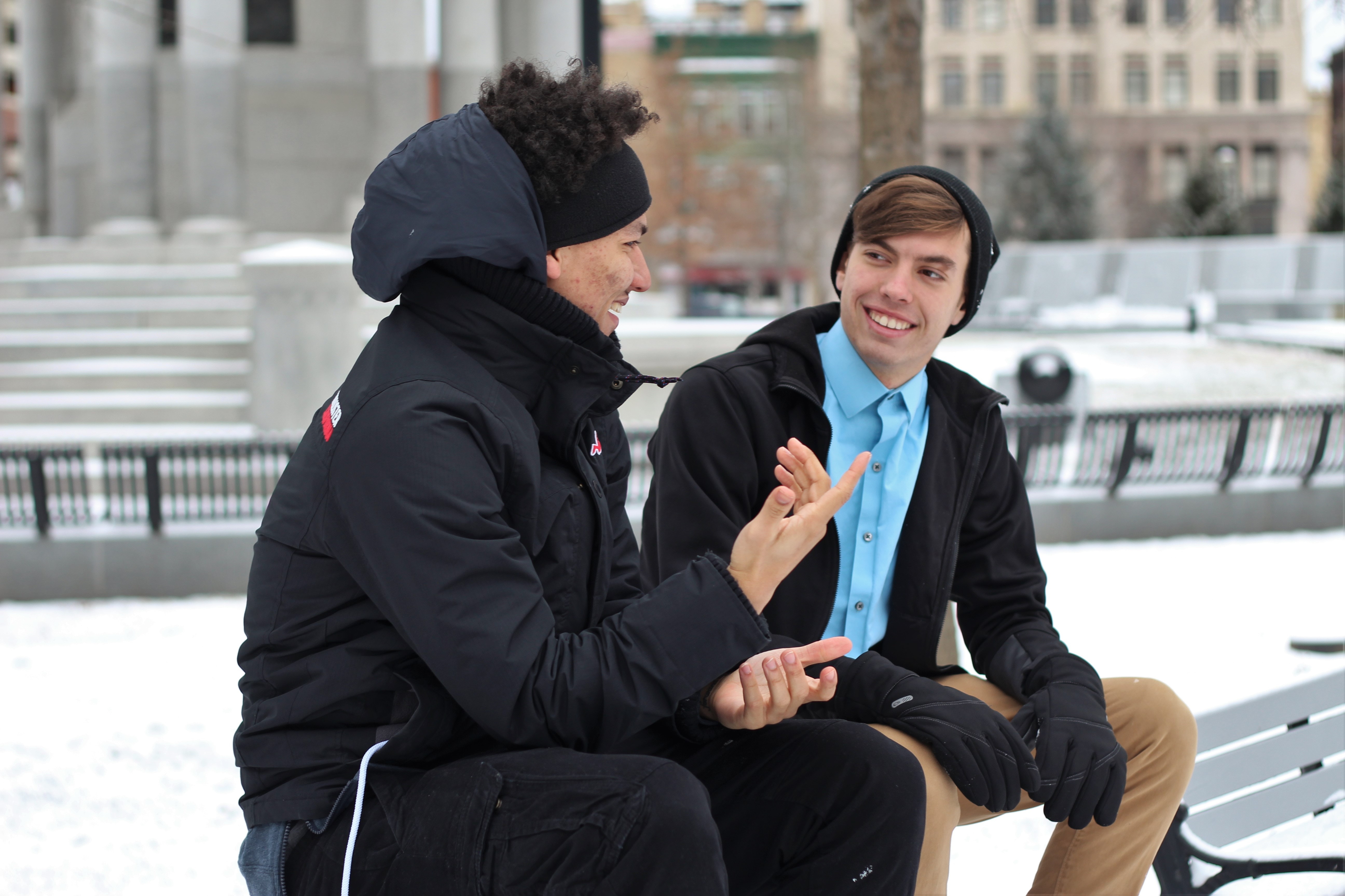 Two men sitting on a bench and chatting.