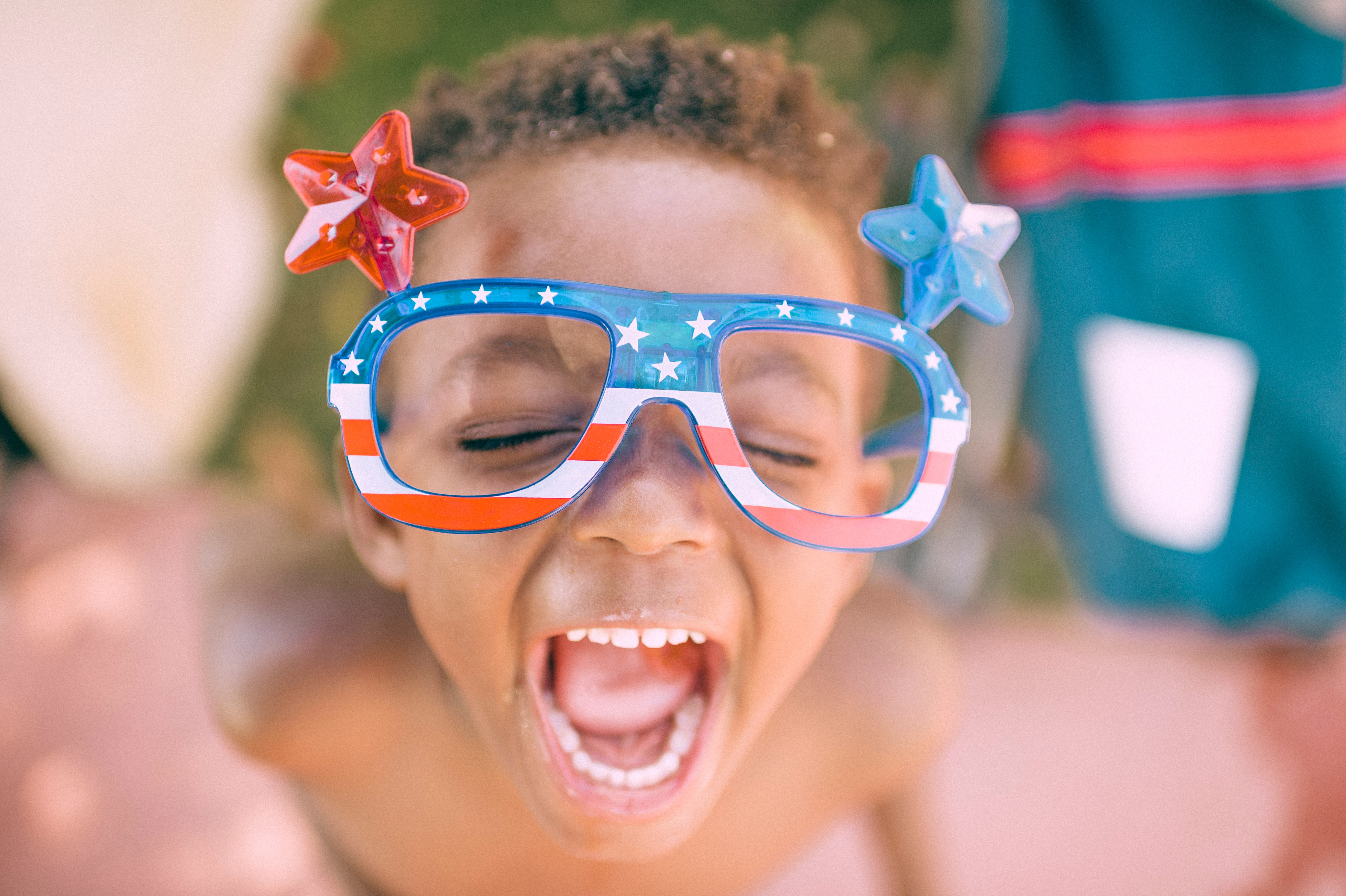 Young boy smiling with USA glasses on.